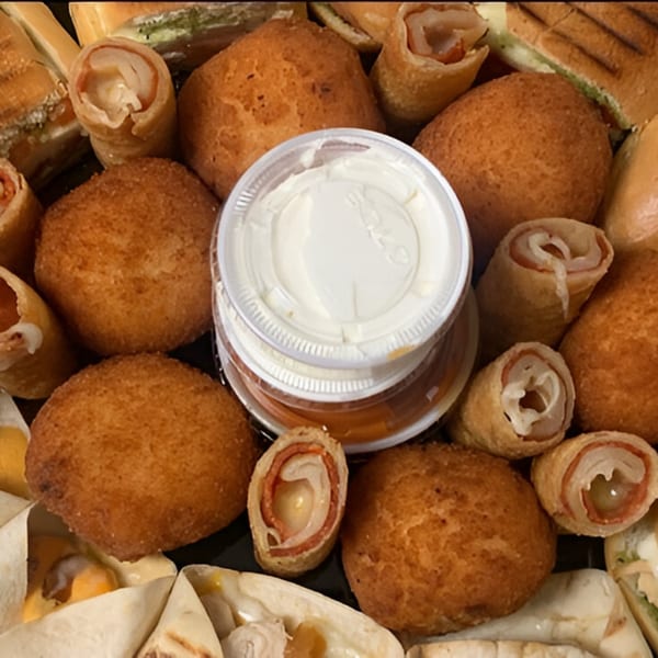 A platter of golden-brown fried appetizers, rolled sandwiches, and dipping sauces from Sandwich Club.